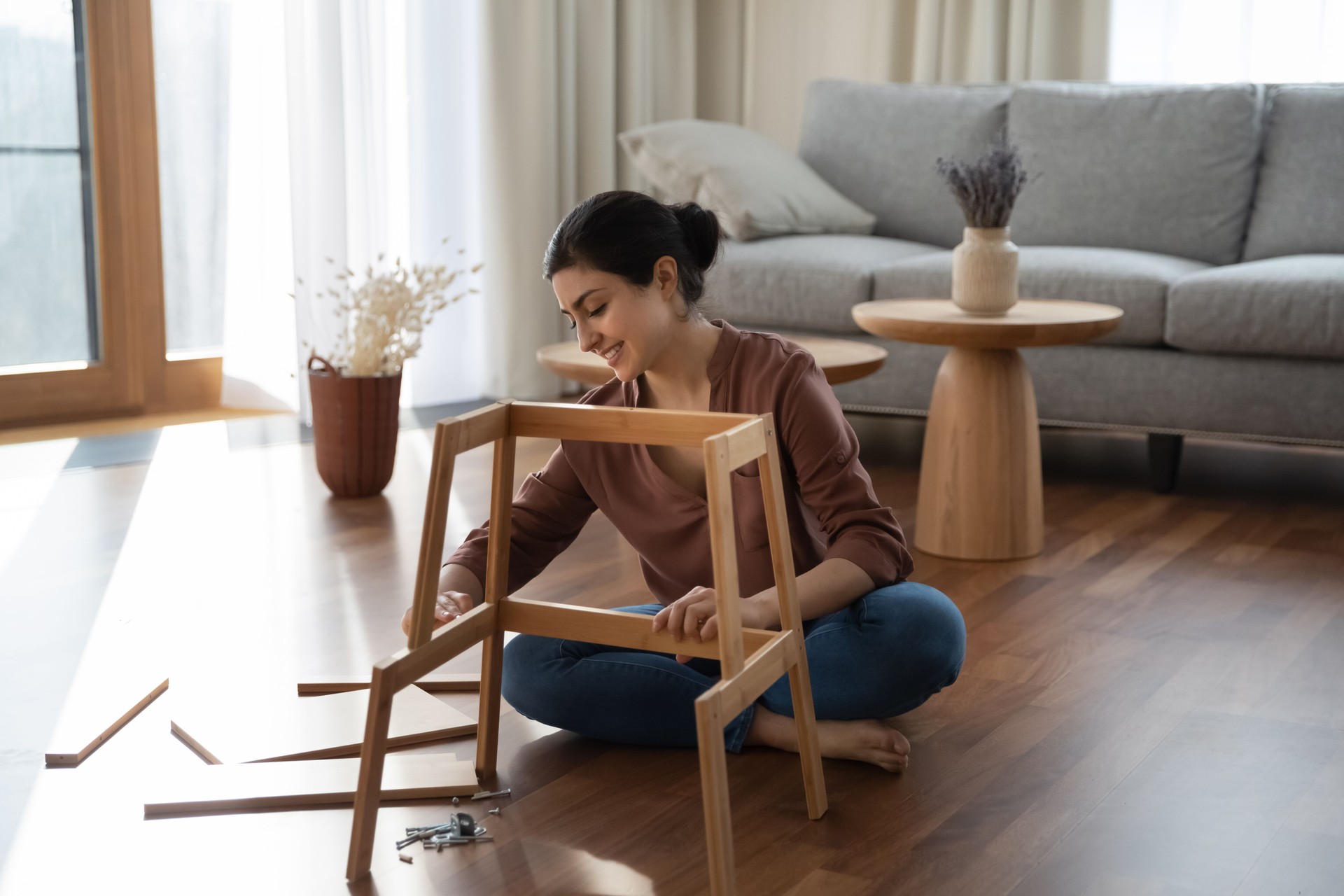 Smiling young indian woman fixing furniture at home.